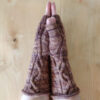 Two hands are clasped, palms together showing the cable detail on the brown knitted mittens they are wearing