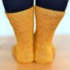 A close up view of the back of a pair of highly-textured gold knitted socks