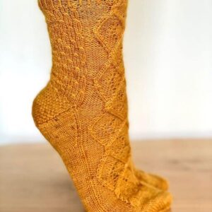 A close up view of feet standing on tiptoe wearing gold coloured knitted socks