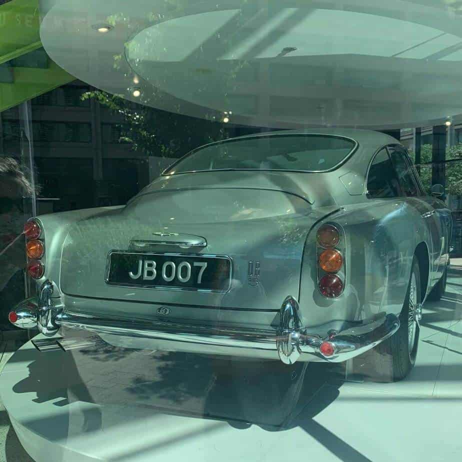 A view of a silver DB5 car with the license plate JB 007 sits on a display under spotlights