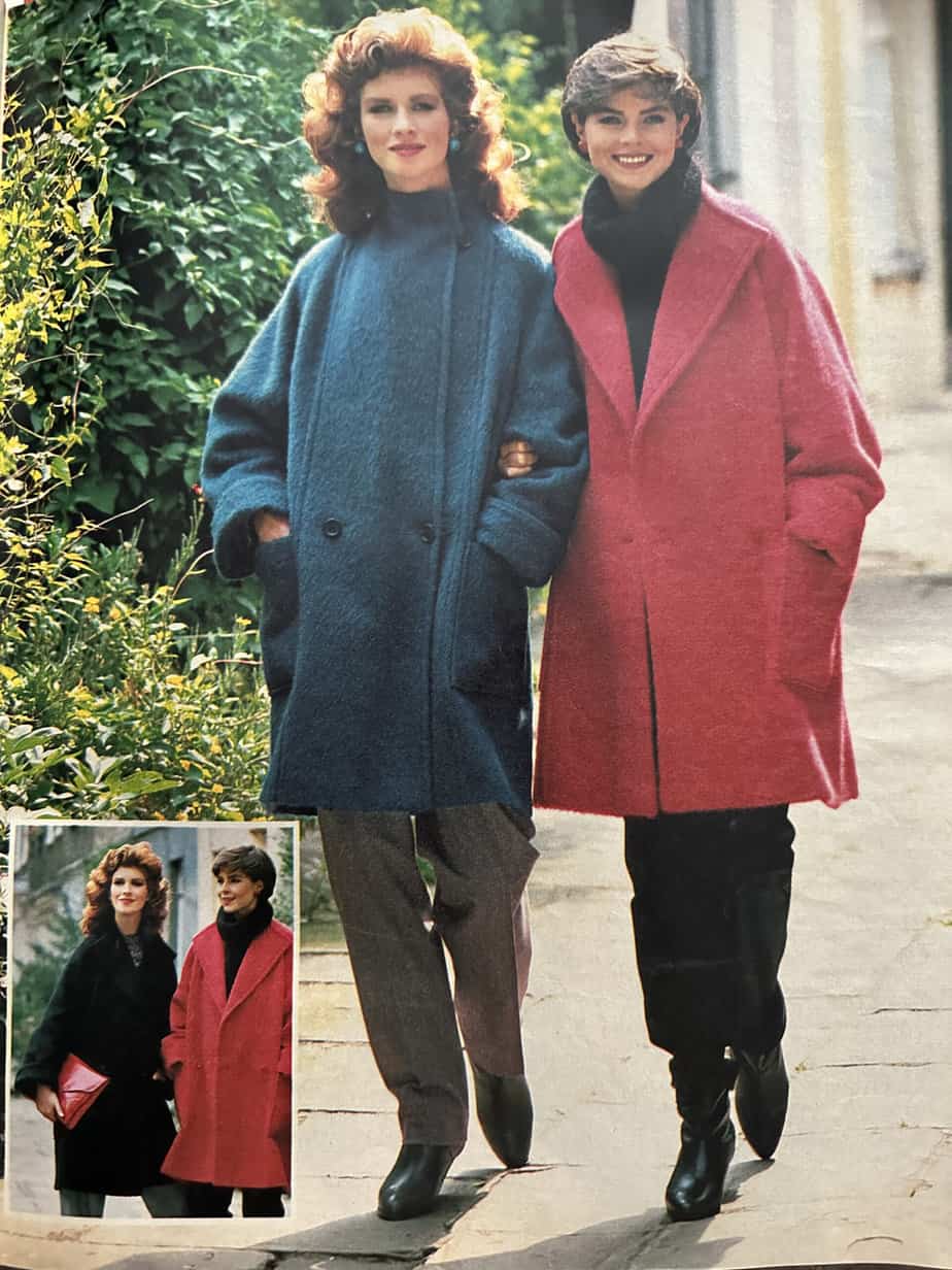 A photograph of a photograph, this image shows two women walking arm in arm along a tree-lined street. The lady on the left is wearing a mid blue double-breasted coat with two buttons at waist level. The lady on the right has a coral pink knee-length coat with large lapels, worn unbuttoned. There is a small image inset to the bottom left of the photograph, picturing the same women; the lady on the left is wearing a black coat in the same style as the pink one.